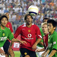 Manchester United's Ruud van Nistelrooy (C) and Beijing Guoan's Cui Wei (L) and Lu Jiang (R) look at the ball during their friendly soccer match at Workers' Stadium in Beijing July 26, 2005.