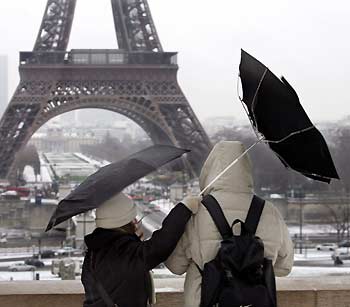 Tourists fight against a gust of wind as they stand near the Eiffel Tower in Paris December 30, 2005. Cold weather conditions have prevailed in France since the beginning of the week with snowfall and icy conditions in many parts of the country.